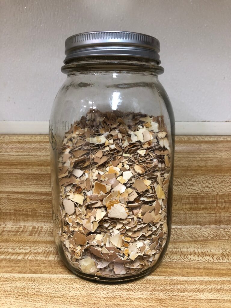 crushed baked eggshells in glass jar on counter