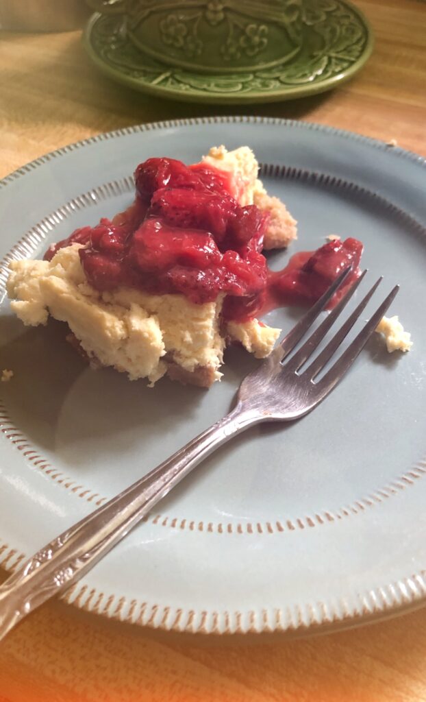 keto strawberry rhubarb cheesecake on blue plate on the counter with a fork