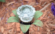 old broom handle pushed in ground with pretty crystal door knob on top
