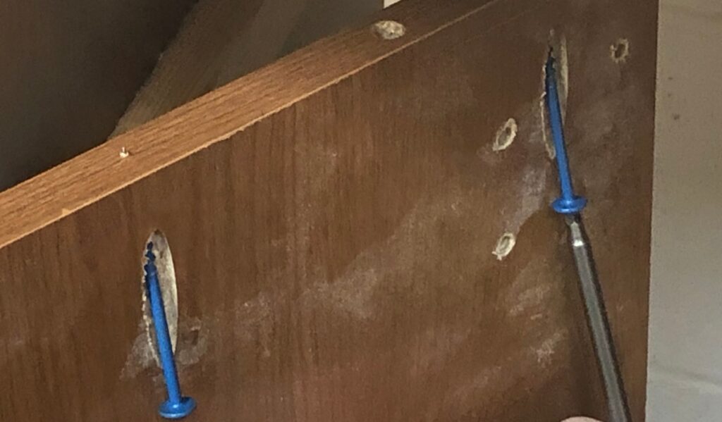 blue screws in the top of a wooden panel